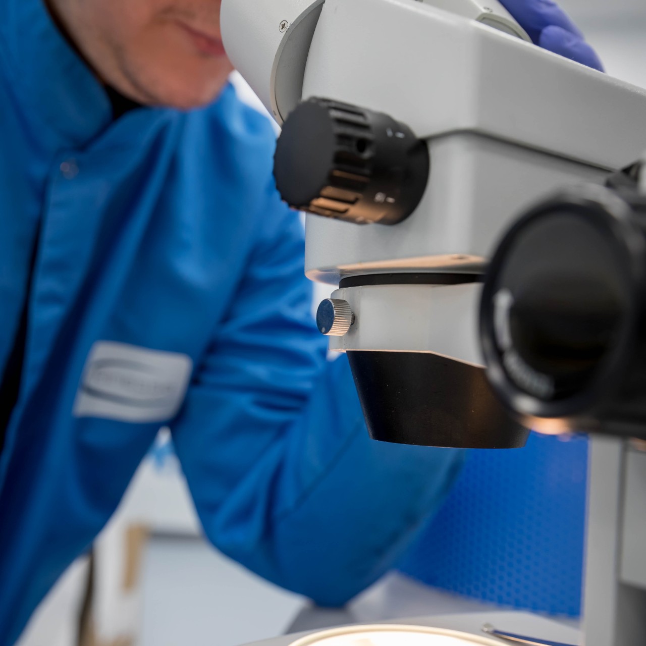 Researcher conducting laboratory tests on adhesive materials in a cleanroom setting, focusing on the development of advanced diagnostic adhesives.